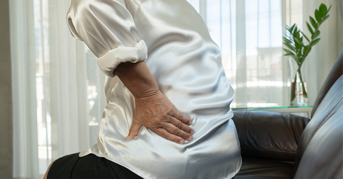 A woman holding her lower back in pain.