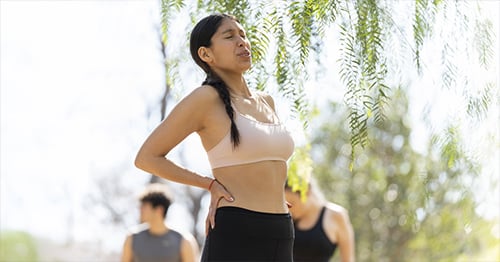 An athletic woman grimacing and holding her hip.