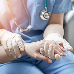 clinician compassionately holds patient's hand
