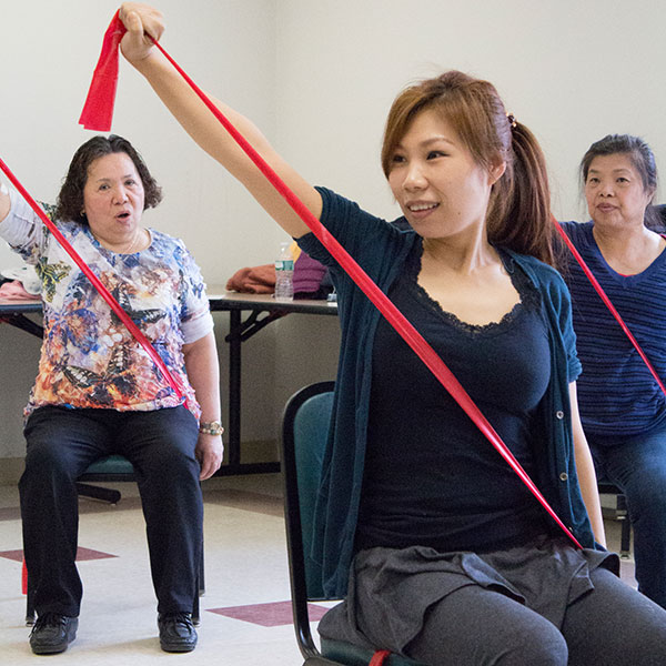 Group of older adult asian women participating in low impact chair exercises.