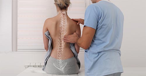 Doctor examining the back of a woman with scoliosis.