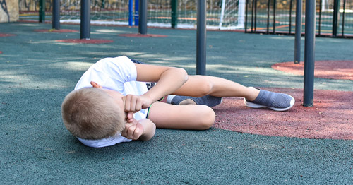 An injured boy on a playground crying.