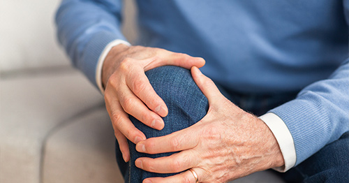 A person holding their arthritic knee in pain.