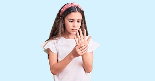 A child with arthritis pain holding her hand.