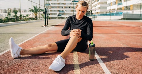 A runner holding her knee in pain.
