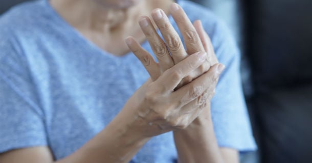 A woman holding her hand in discomfort.
