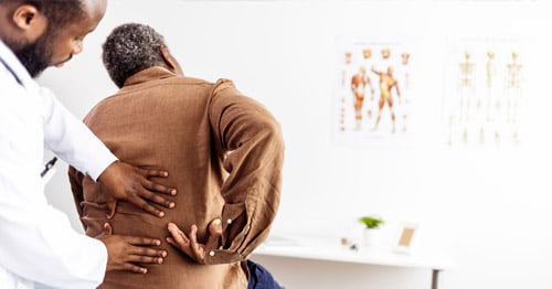 A doctor examinng a patient's lower back.