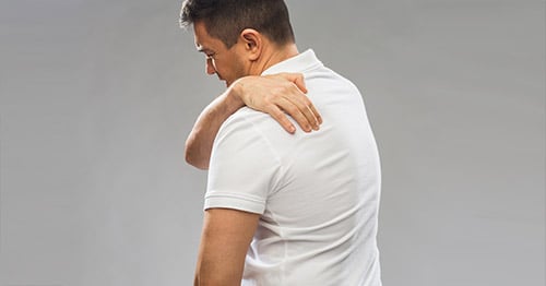 A man holding his shoulder in pain.