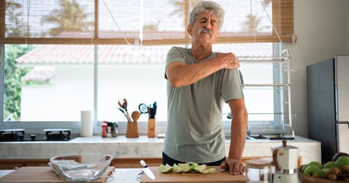 An older man grasping his shoulder in pain.