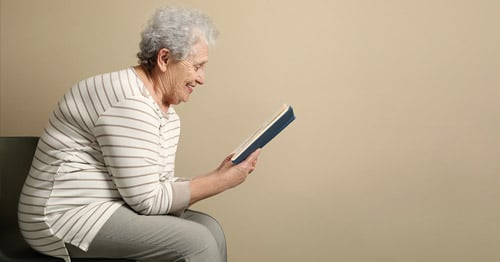 An older woman with kyphosis sitting hunched over.