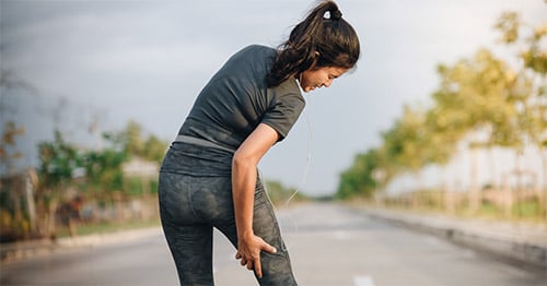 A woman holding her thigh in pain.