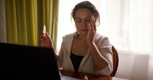 A fatigued woman with eye drops.