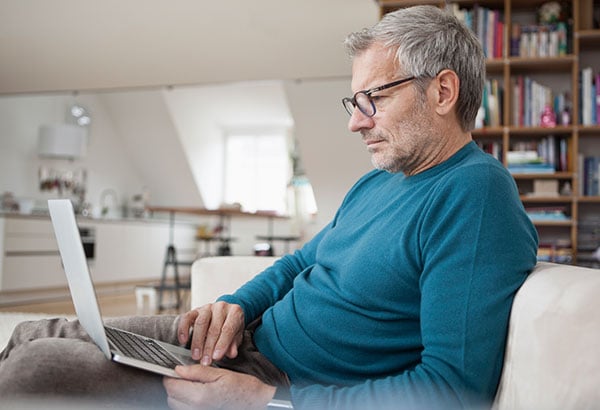 Man sitting on couch reading his laptop
