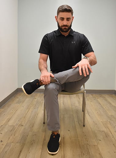 man seated with one leg crossed over the opposite knee