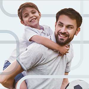 A dad carrying his son on his back.