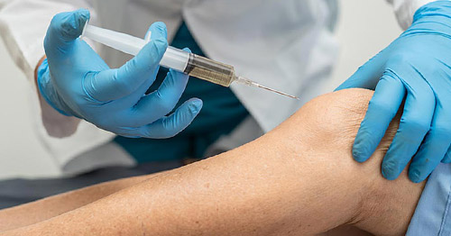 A doctor performing a knee injection.