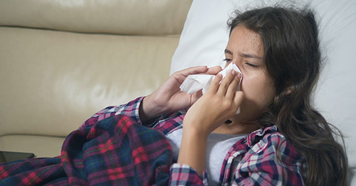 A teenage girl blowing her nose.