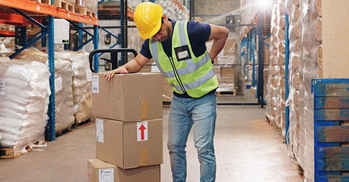 A warehouse worker holding his lower back in pain.